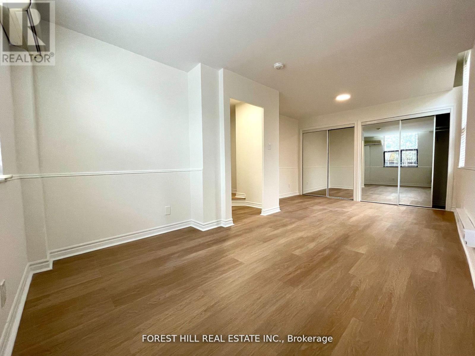 A spacious room with wooden flooring and white walls.