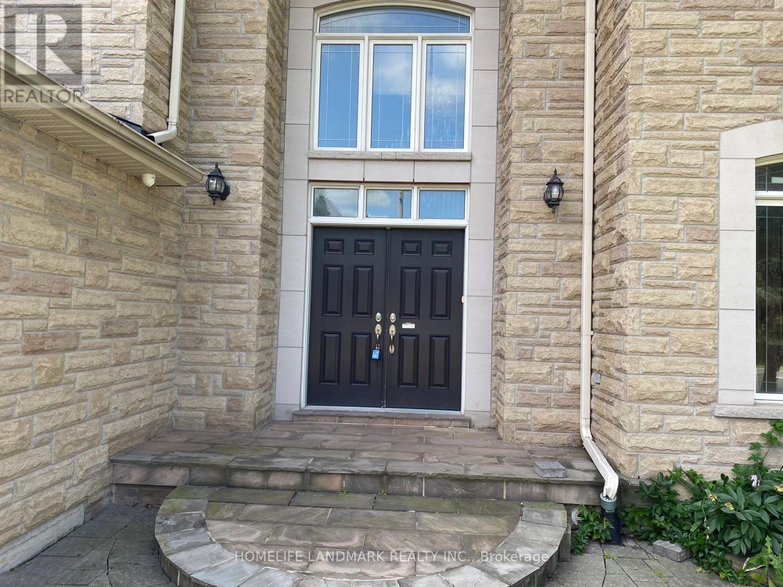 A stone house with a black door and steps leading to it.