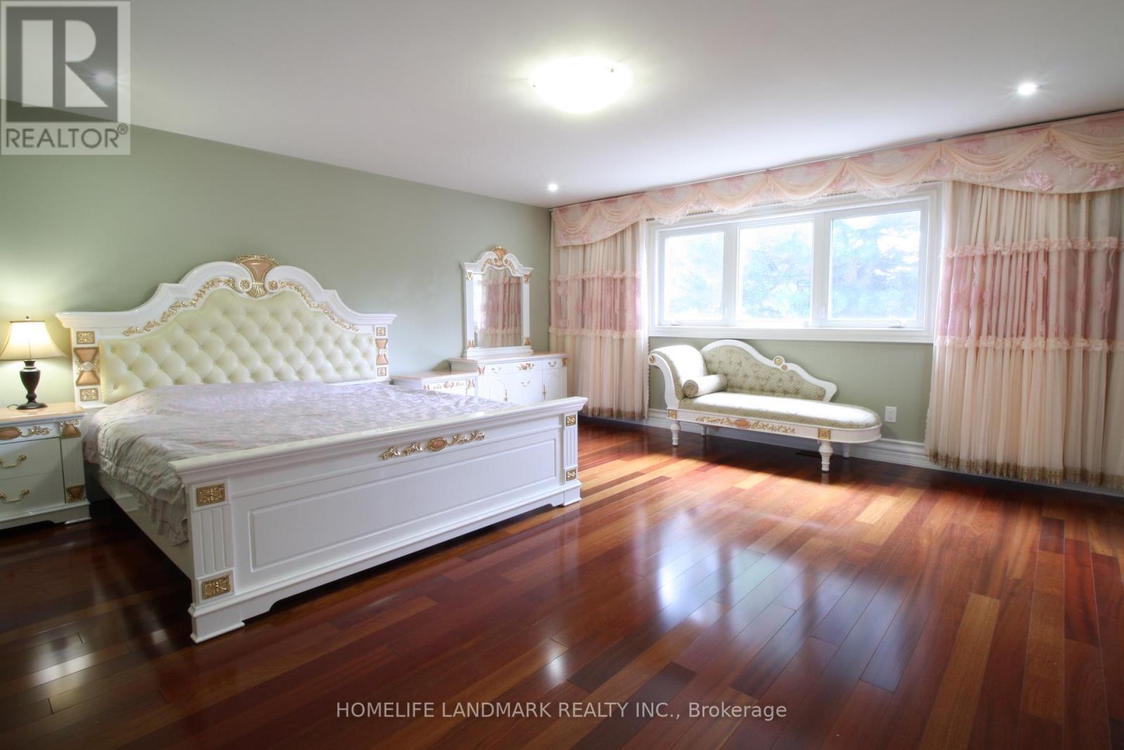 A bedroom with a large bed and a smaller bed with a window.