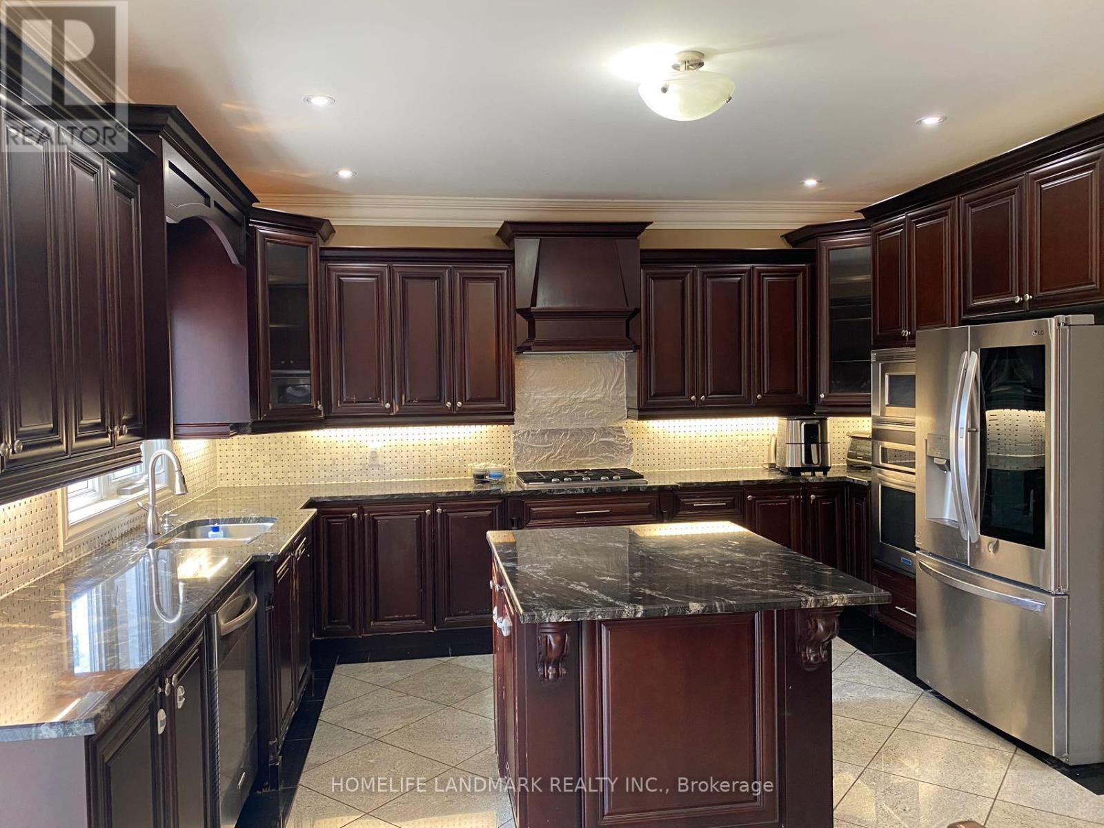 A kitchen with dark wood cabinets and a marble island.