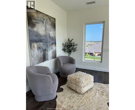 A living room with two grey chairs and a large abstract painting on the wall.