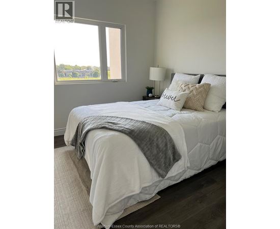 A bedroom with a large bed and a window overlooking a field.