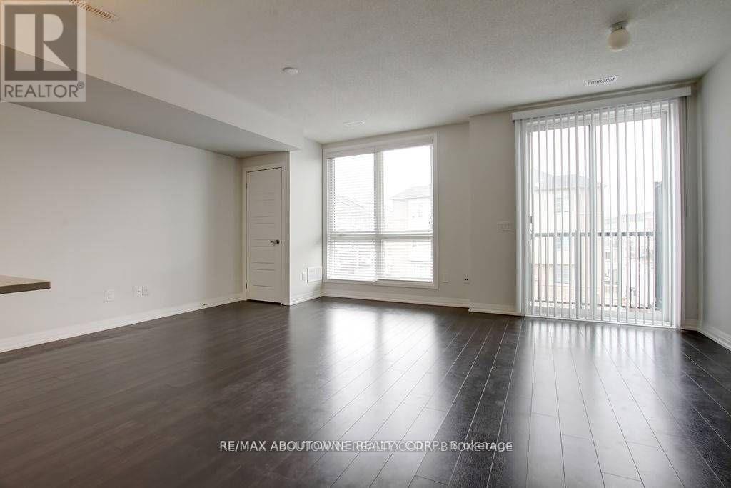 A spacious room with wooden flooring and a sliding glass door.