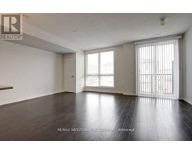 A spacious room with wooden flooring and a sliding glass door.