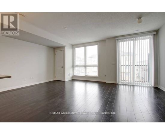 A spacious room with wooden flooring and a sliding glass door.