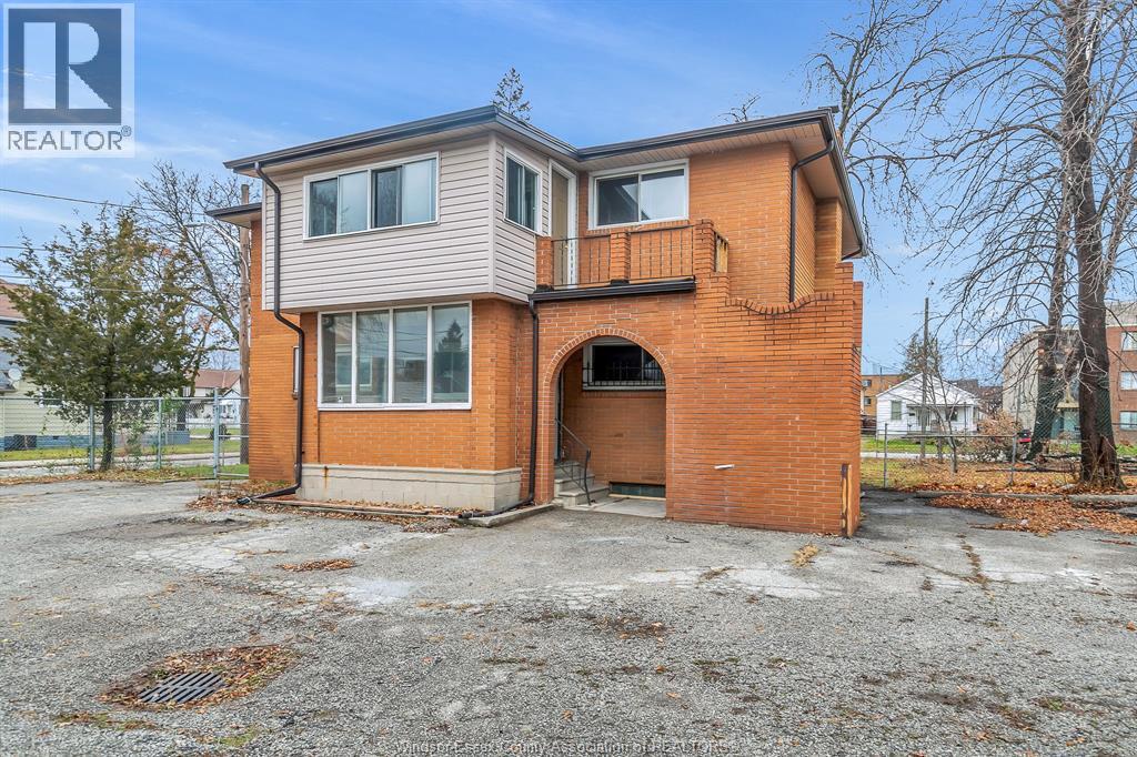 A two-story brick house with a balcony on the second floor.