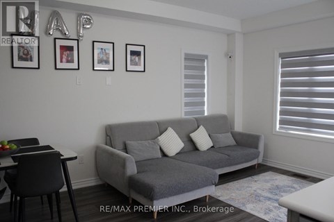 A living room with a grey couch and a dining table.