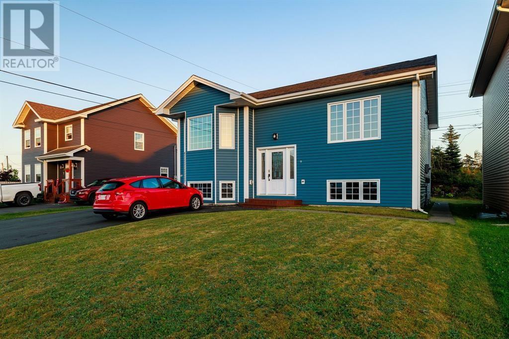 A red car is parked in front of a blue house.