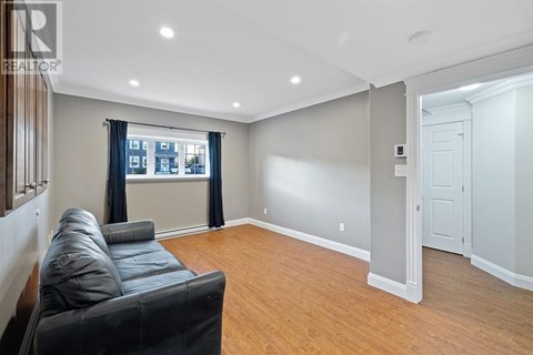A living room with a black leather couch and a window with curtains.
