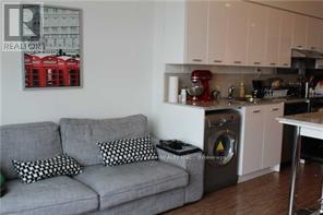 A grey couch with two pillows sits in a kitchen.