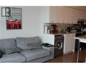 A grey couch with two pillows sits in a kitchen.