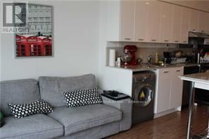 A grey couch with two pillows sits in a kitchen.