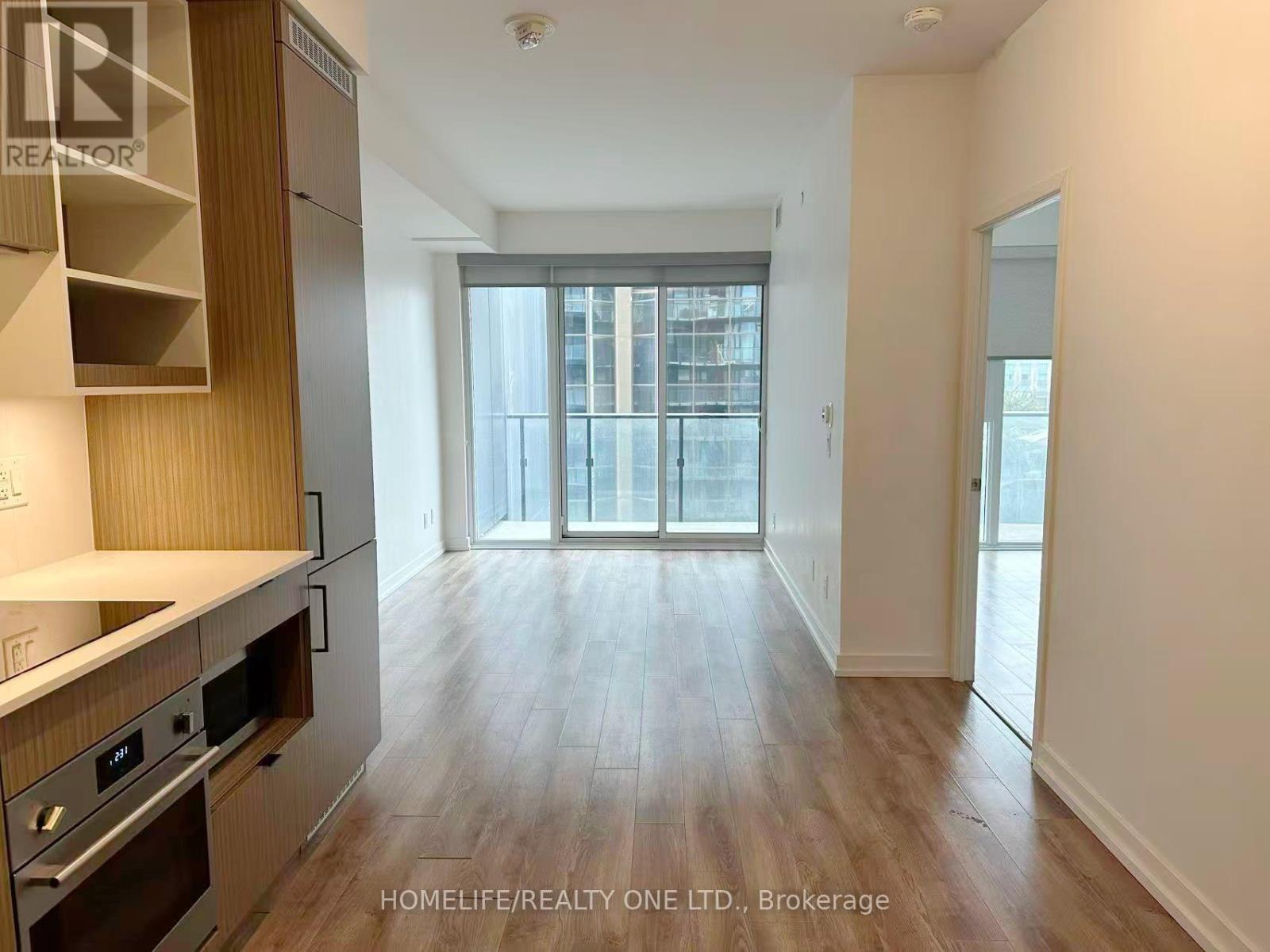 A spacious kitchen with wooden cabinets and a stainless steel oven.