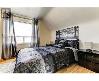 A bedroom with a bed, nightstand, and window.