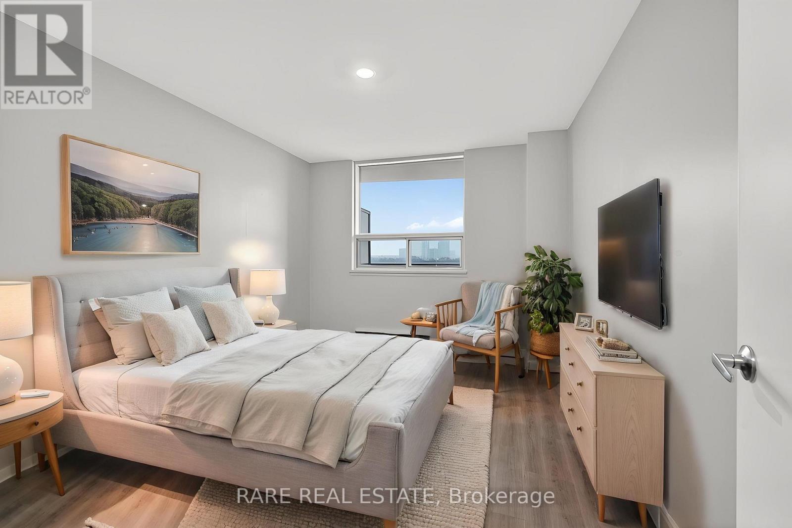 A bedroom with a large bed, a chair, a desk, and a painting on the wall.
