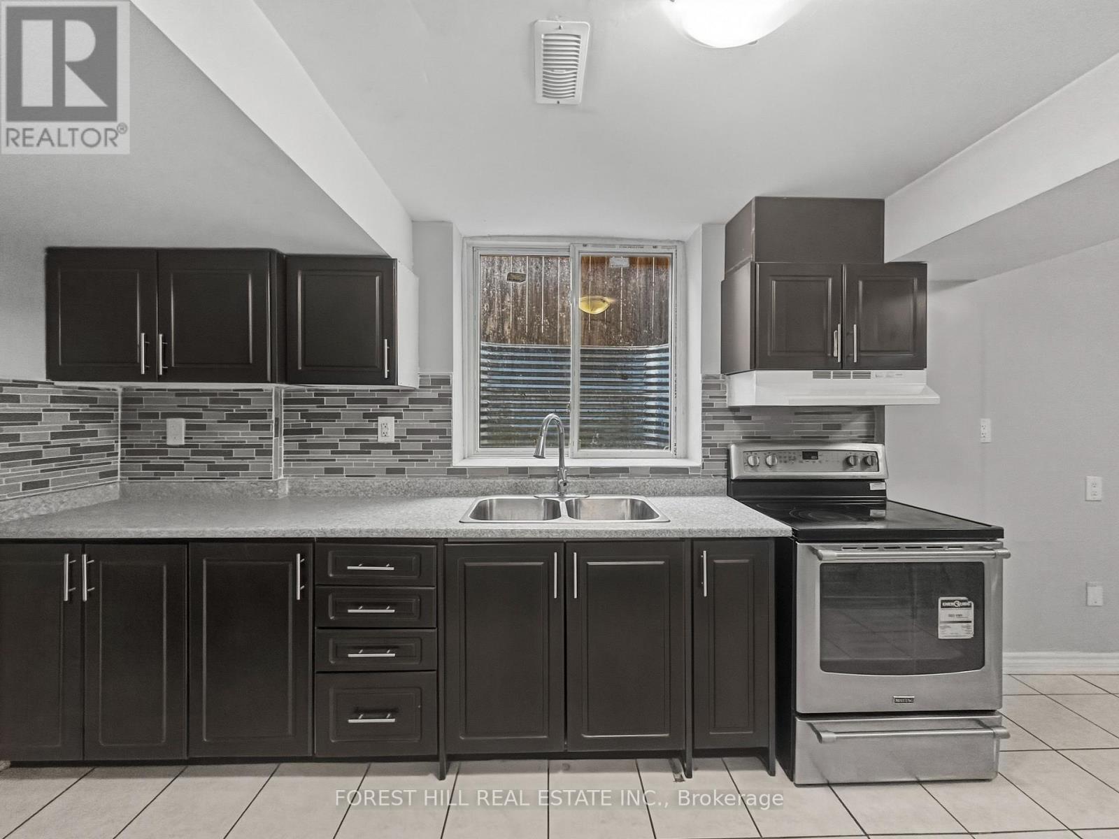 A kitchen with black cabinets and a stone counter.