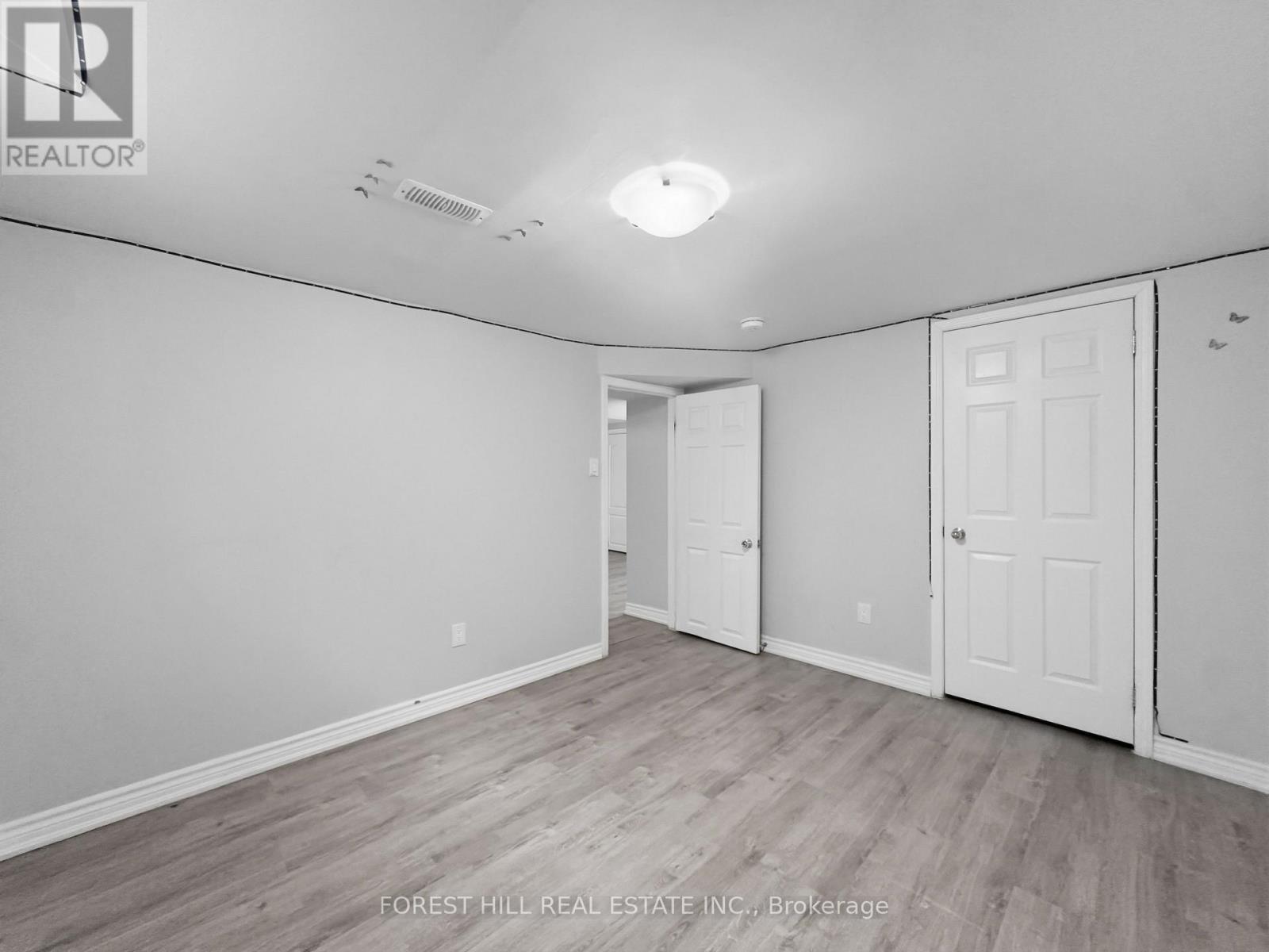 A spacious room with wood flooring and white walls.