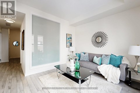 A living room with a grey couch and a glass coffee table.
