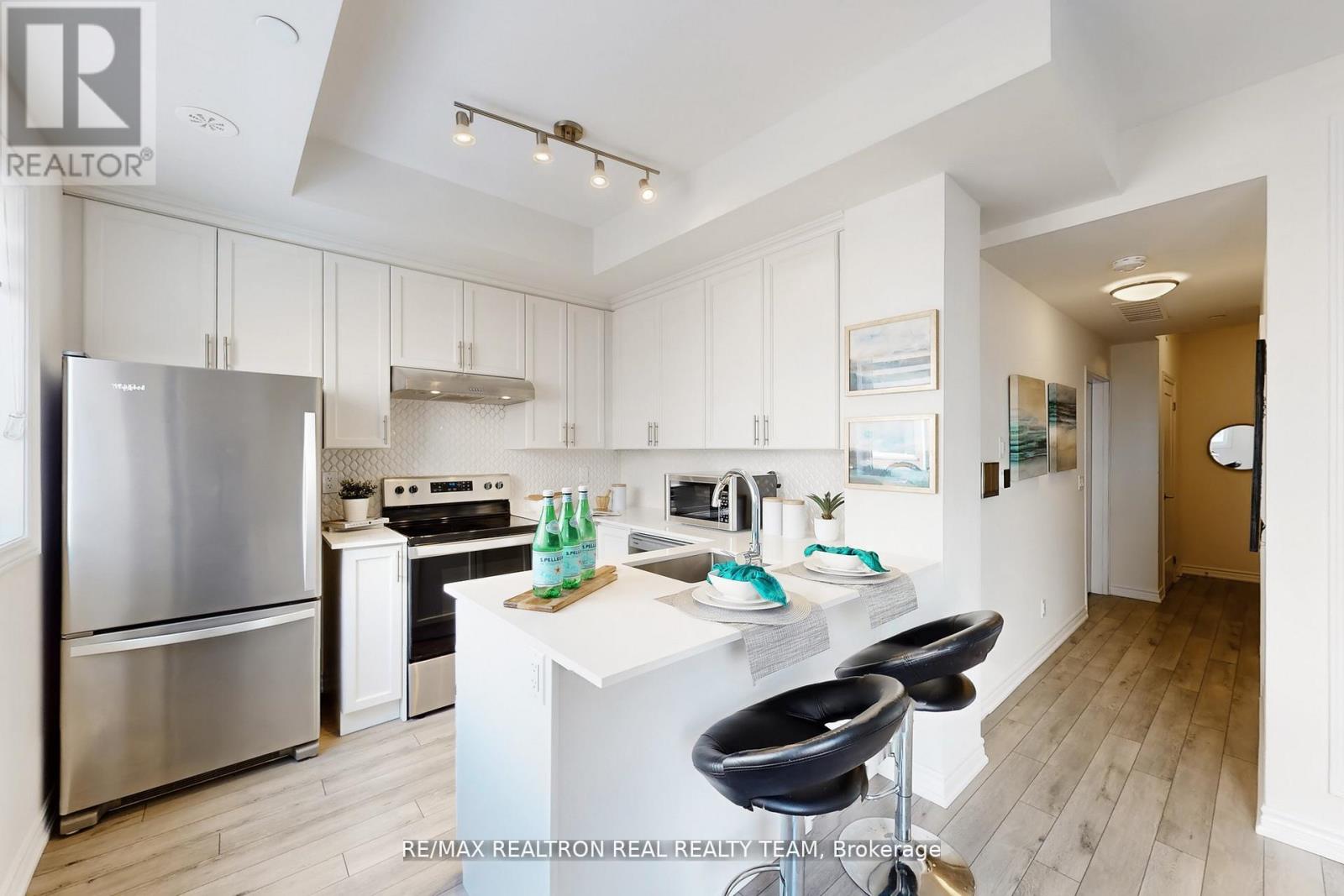 A modern kitchen with white cabinets and a stainless steel refrigerator.