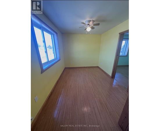 A room with a ceiling fan and wooden flooring.