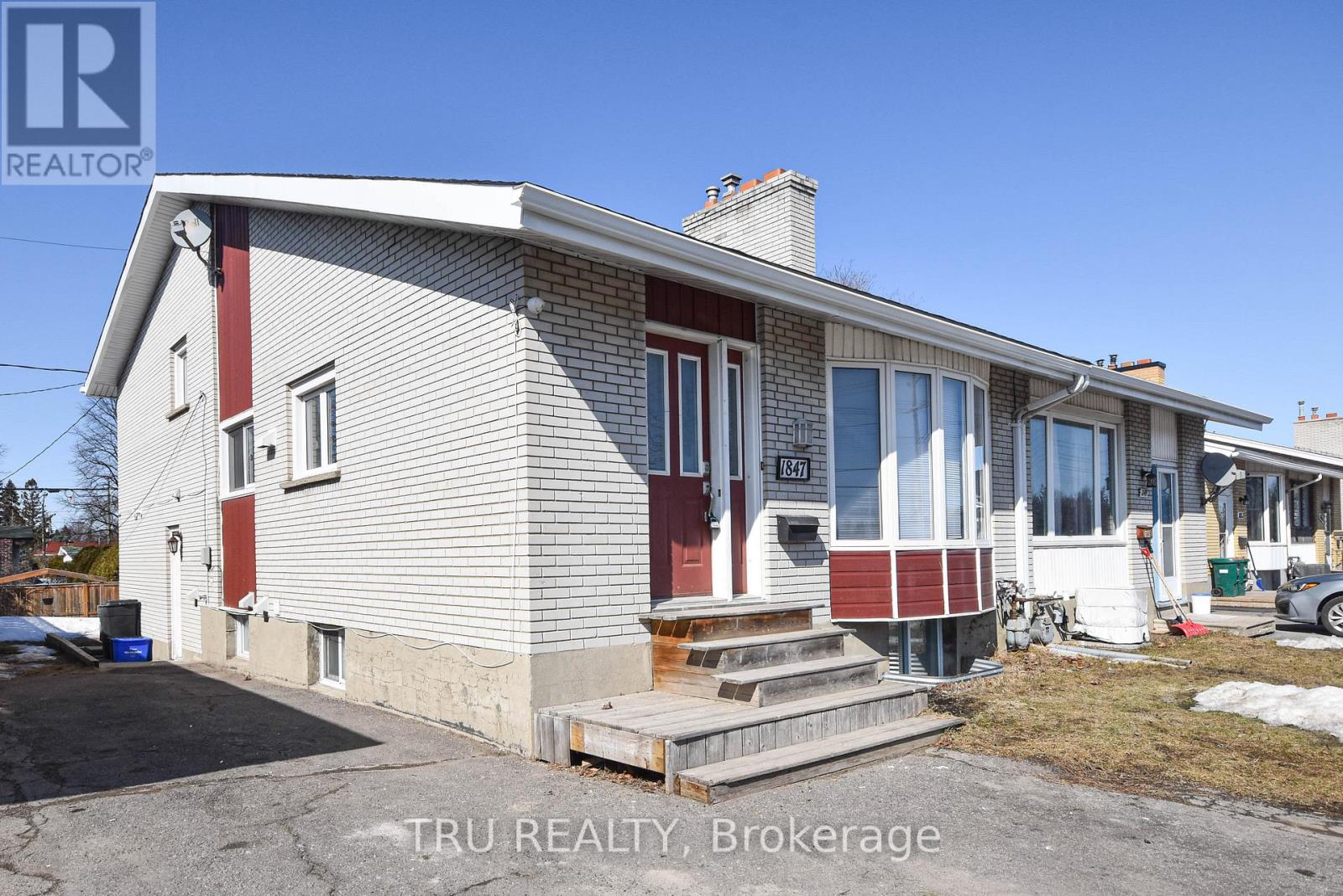 A house with a red and white exterior is for sale through Tru Realty Brokerage.
