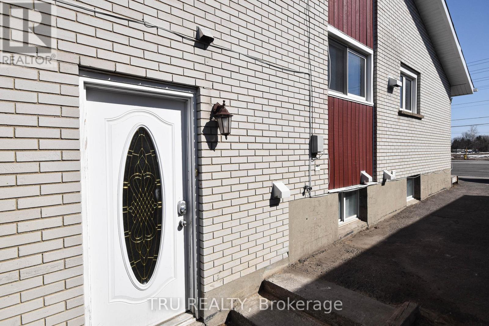 A white door with a window in the middle of a brick wall.