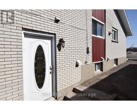 A white door with a window in the middle of a brick wall.