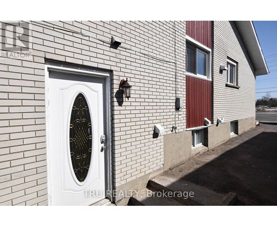 A white door with a window in the middle of a brick wall.