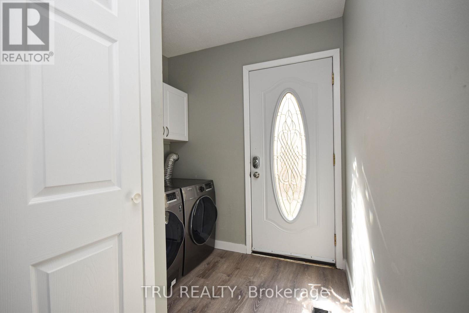 A white door with a window in the middle is open to a laundry room.