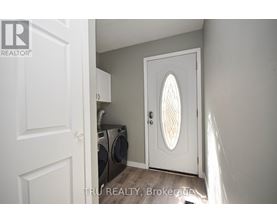A white door with a window in the middle is open to a laundry room.