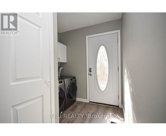 A white door with a window in the middle is open to a laundry room.