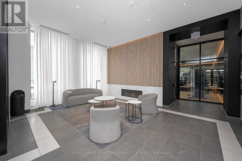 A modern living room with a grey sofa and a black trash bin.