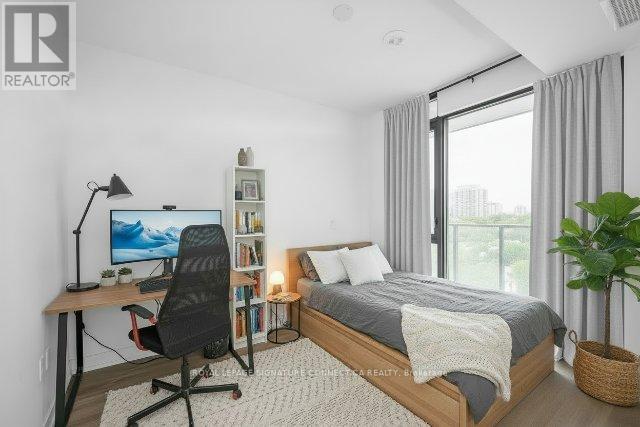 A bedroom with a bed, desk, chair, and a window with curtains.
