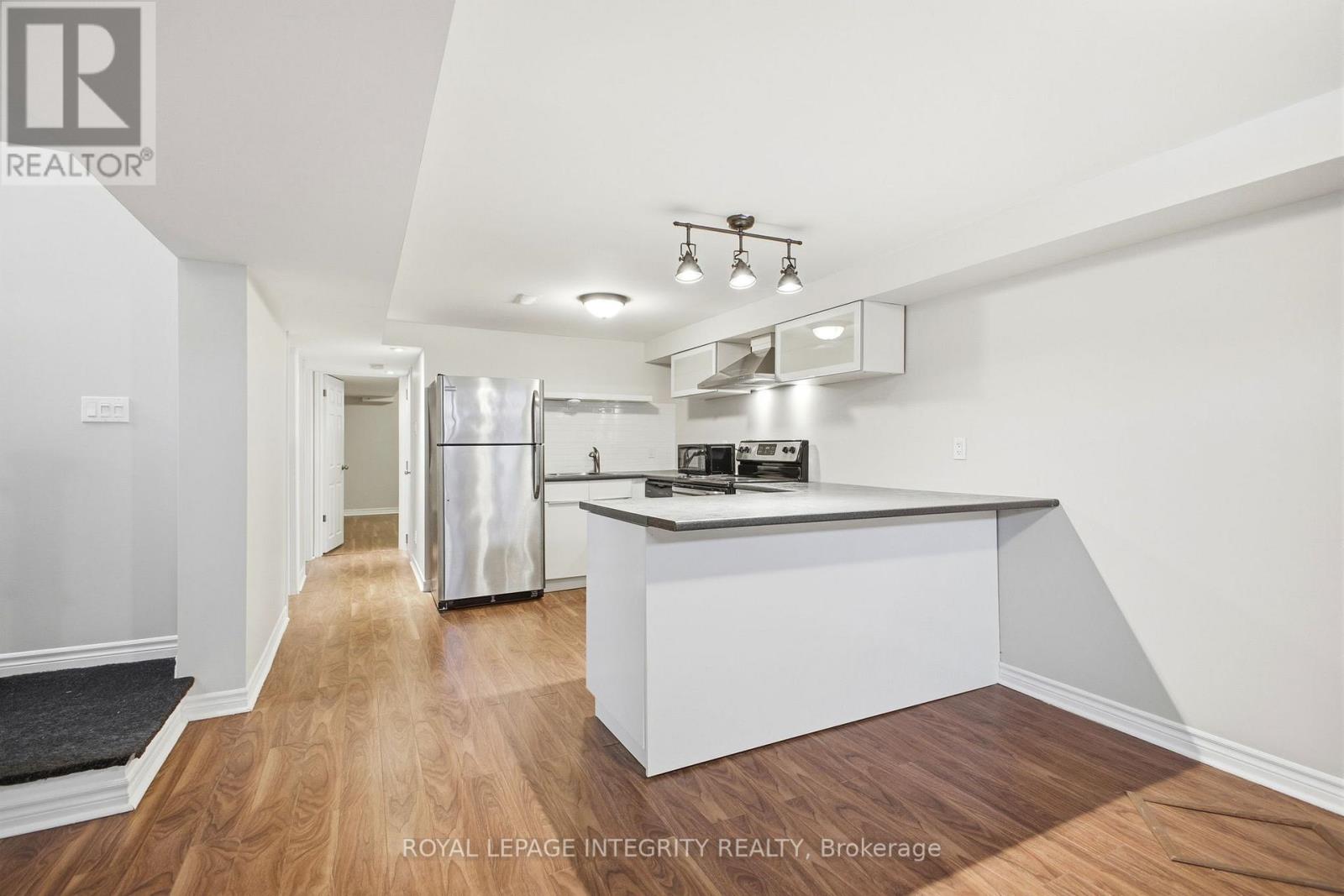 A modern kitchen with white cabinets and a wooden floor.