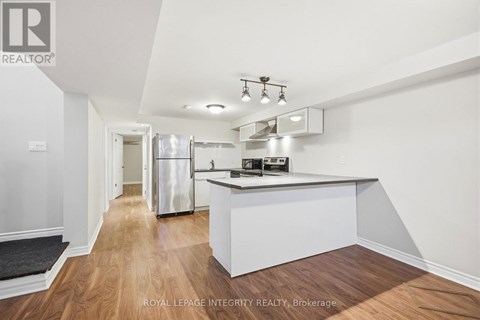A modern kitchen with white cabinets and a wooden floor.