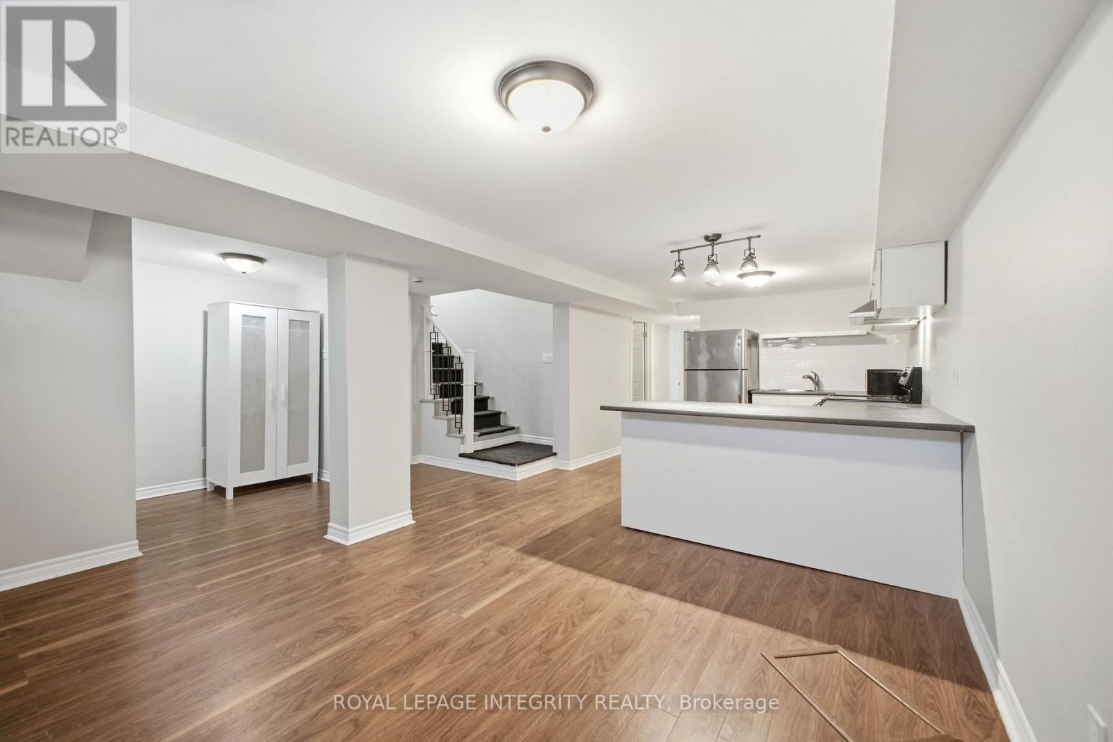 A spacious room with wooden flooring and white walls.
