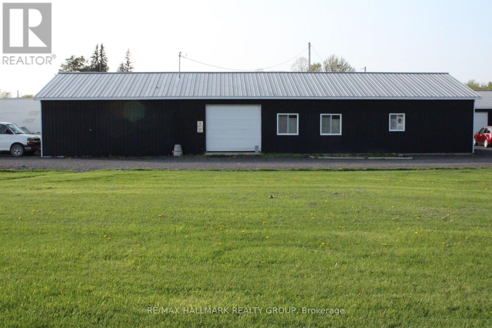 A black building with a white door and windows is in the foreground with a car parked in front of it.