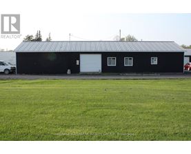 A black building with a white door and windows is in the foreground with a car parked in front of it.
