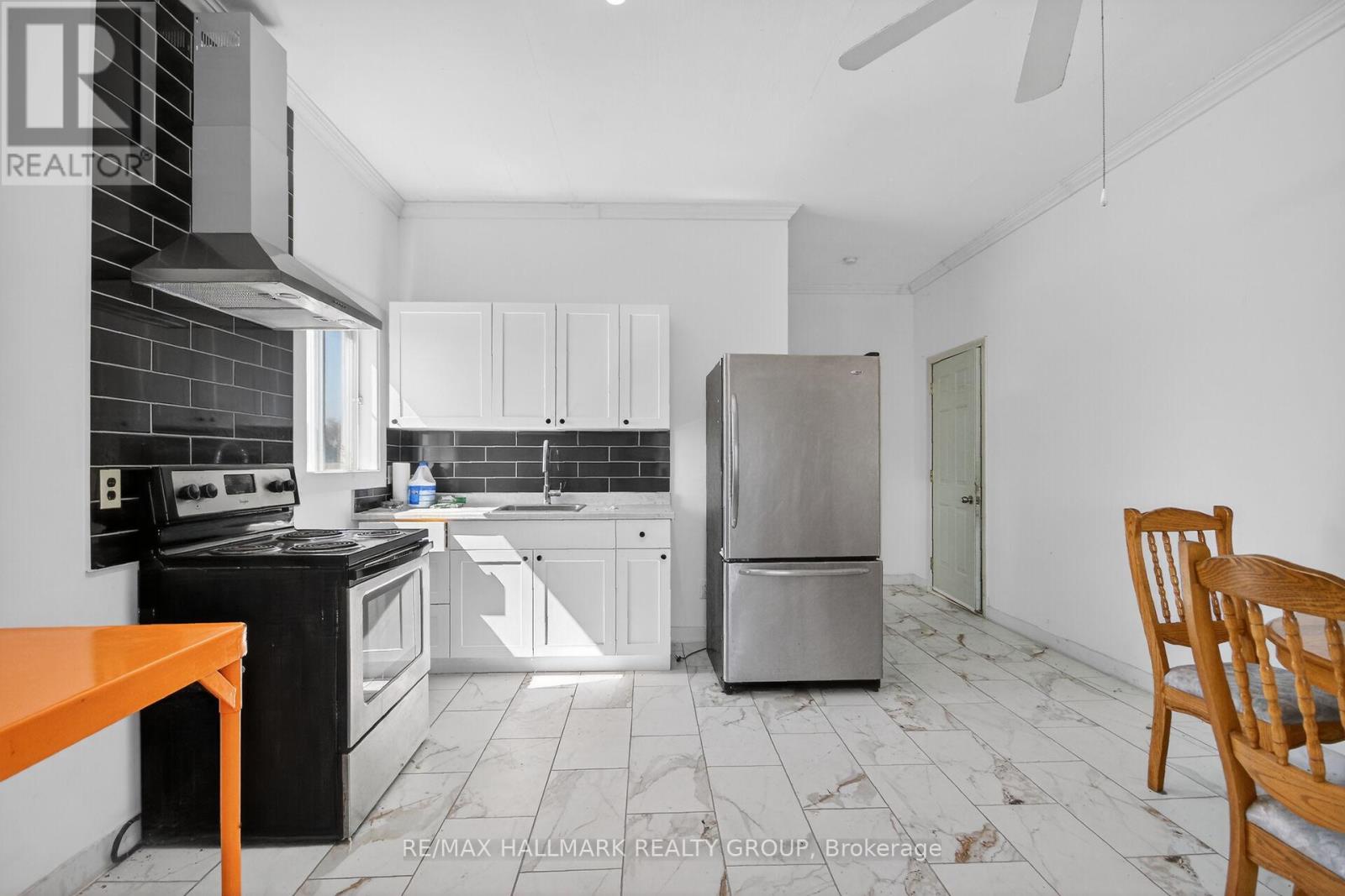A kitchen with black and white appliances and a wooden chair.
