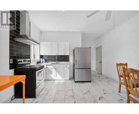 A kitchen with black and white appliances and a wooden chair.