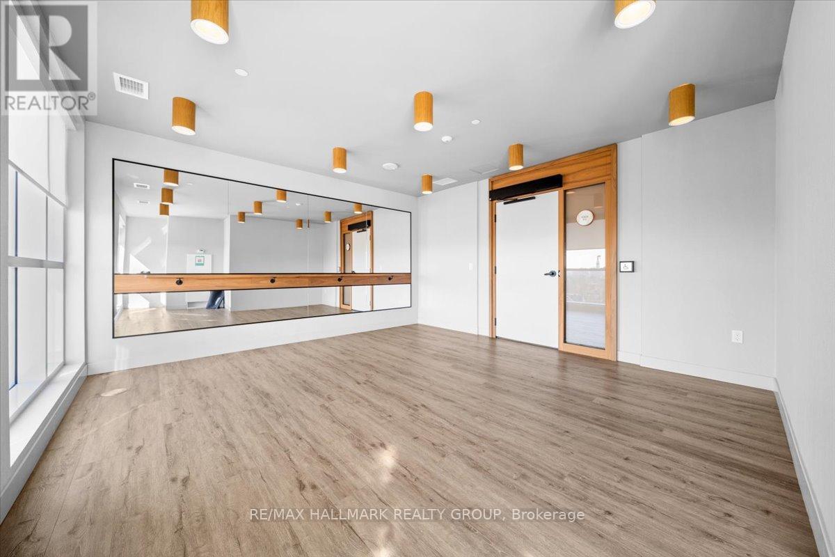 A spacious room with wooden flooring and a large mirror on the wall.