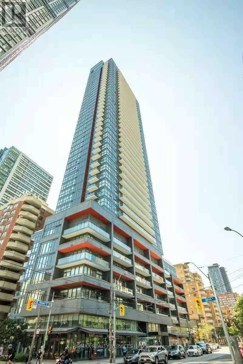 A tall building with a blue and red stripe on the side stands out in a city street.