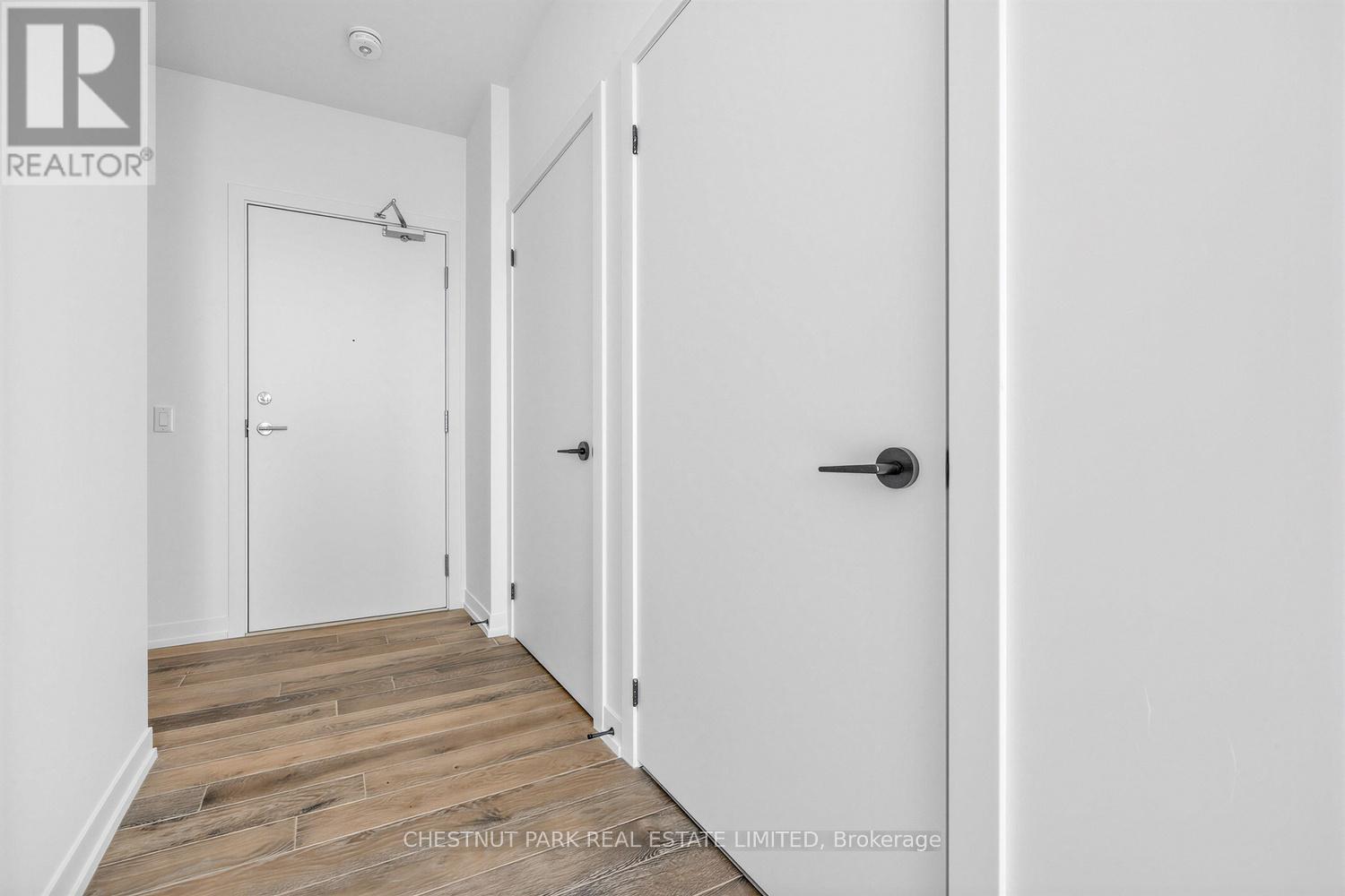A hallway with a door on the right and a white door on the left.