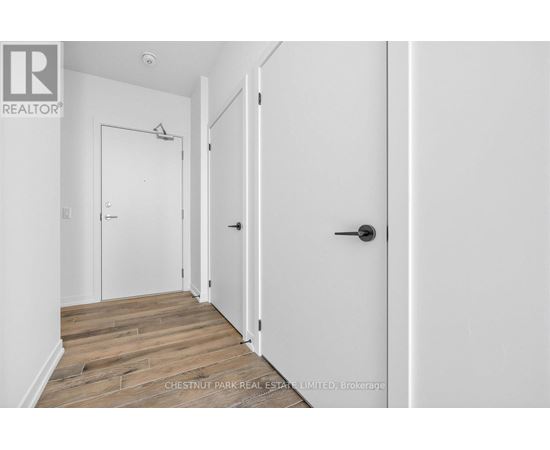 A hallway with a door on the right and a white door on the left.