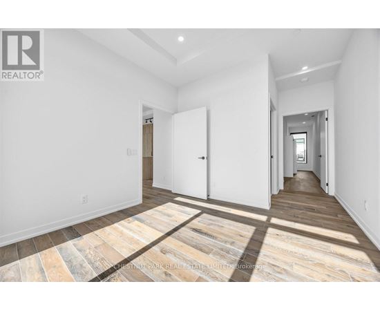A spacious room with a wooden floor and white walls.