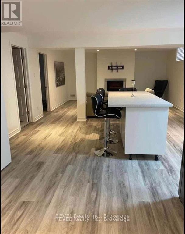 A white desk with a chair and a lamp stands in a room with light wood flooring.