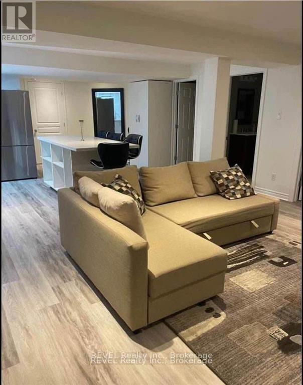 A beige couch with a black chair and a mirror in a room.