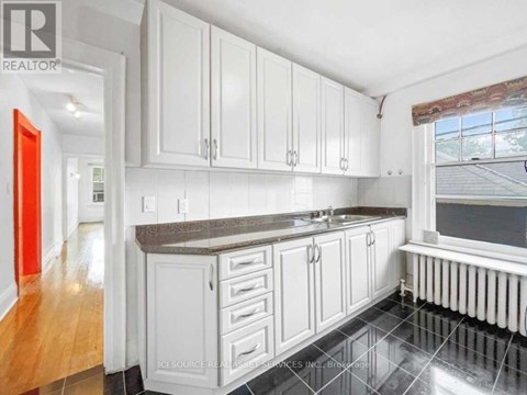 A kitchen with white cabinets and a black countertop.