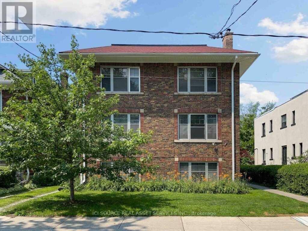 A red brick house with a tree in front.