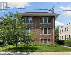 A red brick house with a tree in front.